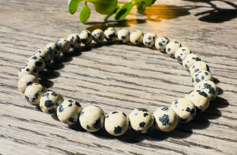 Beaded bracelet with black speckles on a wooden surface