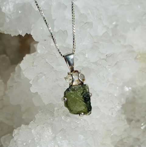 Green stone pendant on a silver chain against a white crystal background