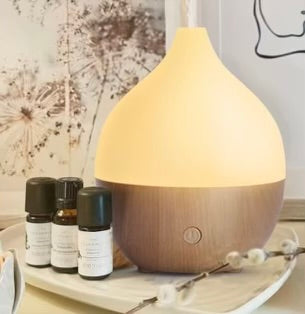 Aromatherapy diffuser with essential oil bottles on a wooden surface.