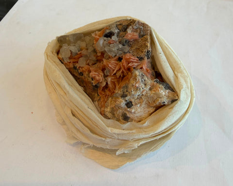 Multi-mineral specimen showing orange crystal fans, clear points, and dark metallic inclusions