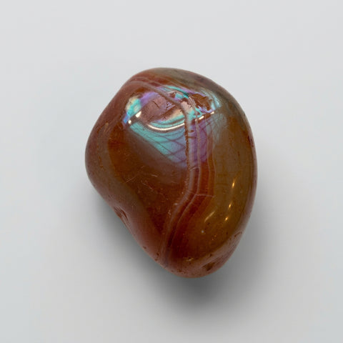 Single banded polished carnelian tumbled stone in reddish-brown on a studio background