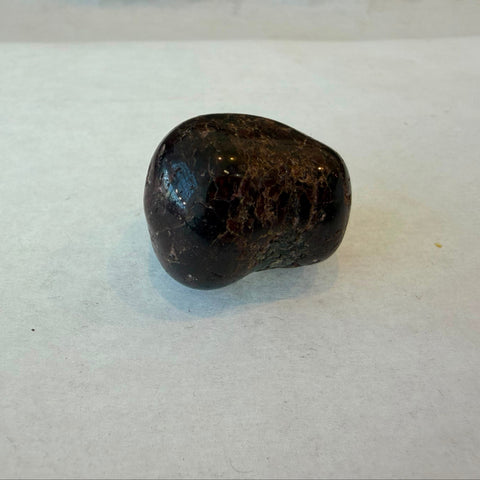 Bowl of polished garnet tumbled stones in deep red-brown gemstone tones