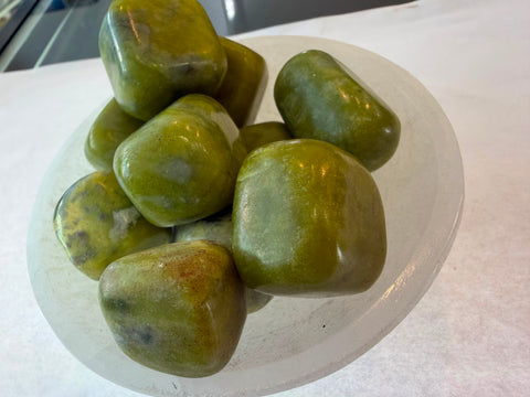 Bowl of polished olive jade tumbled stones in moss and olive green tones
