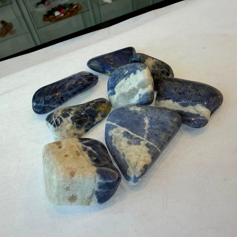 Group of polished sodalite tumbled stones in deep blue with white veining