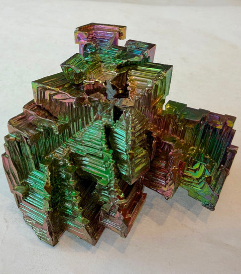 Lab-grown bismuth crystal showing terraced stair-step hopper formation and rainbow colors