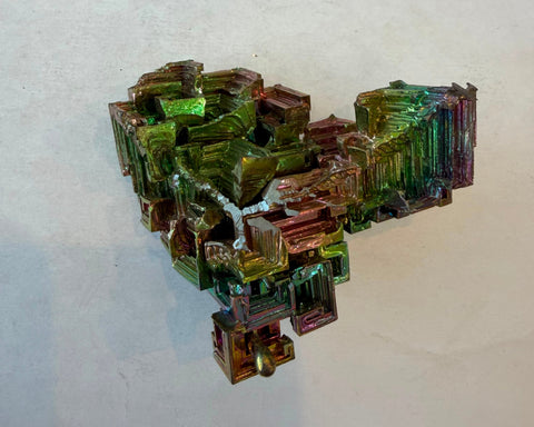 Close view of bismuth crystal iridescence shifting between green, pink, and gold