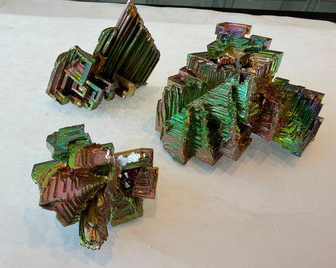 Group of rainbow bismuth crystals showing range of geometric formations and iridescent colors
