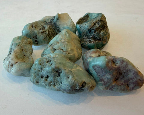 Group of raw Larimar stones showing natural variation in blue, white, and grey patterning