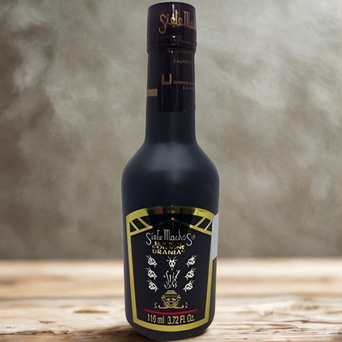 Bottle of Sella Macci with a gold label on a wooden surface and gray background